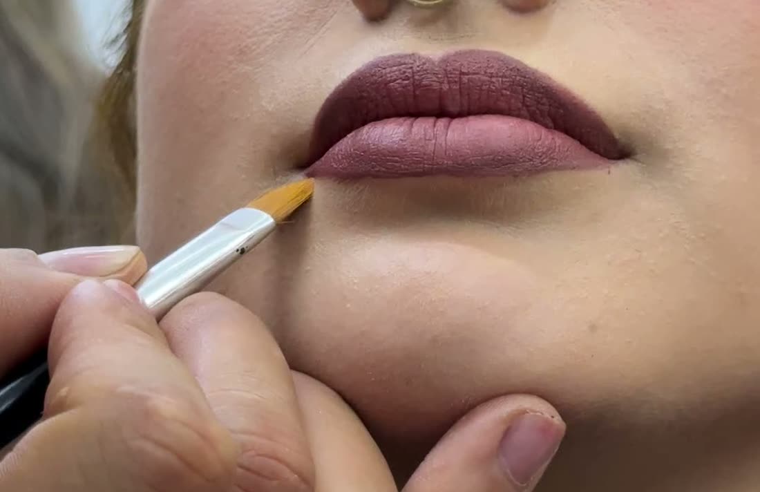 Detalle de aplicación de labial durante un maquillaje profesional